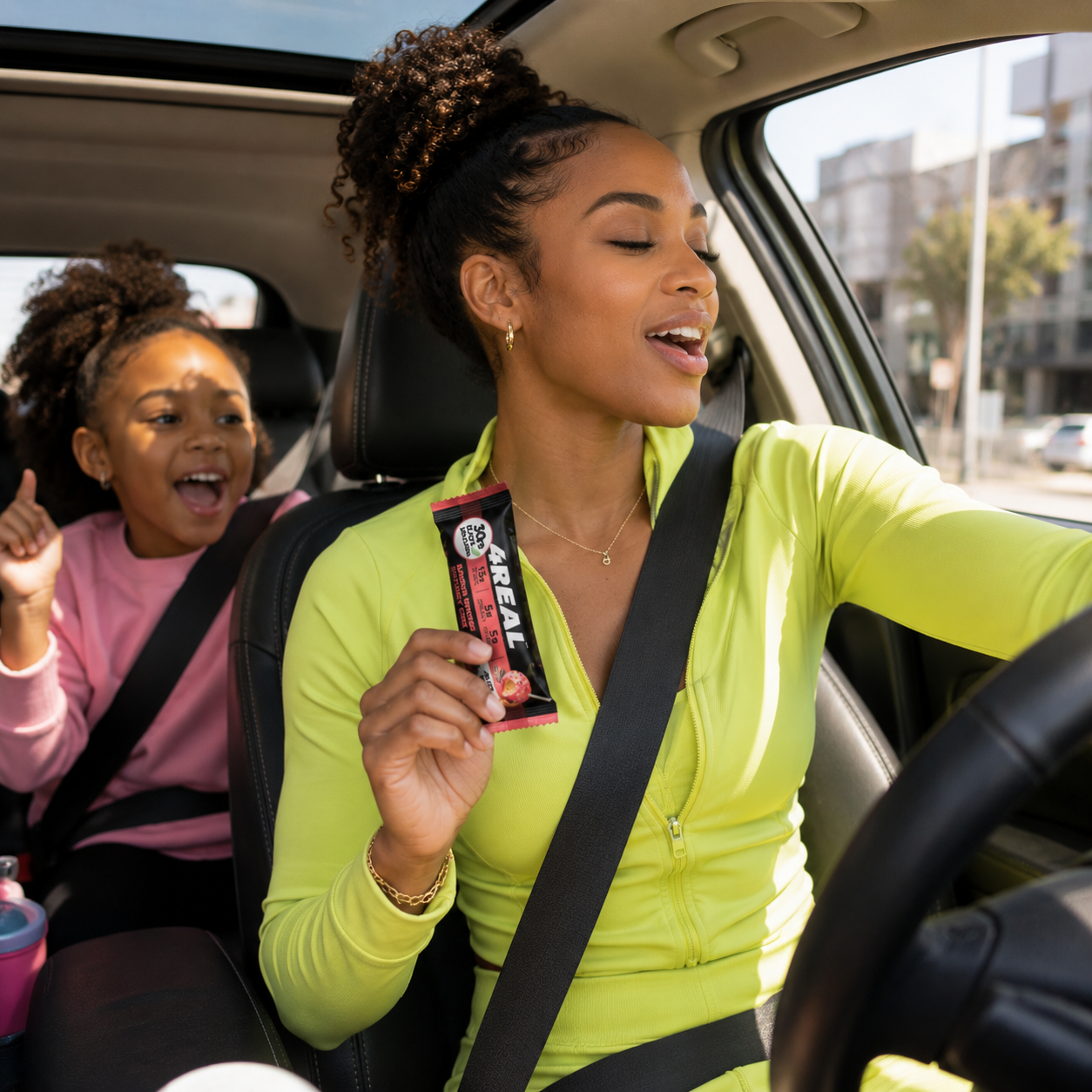 A mom and daughter singing in the car, holding a 4REAL bar
